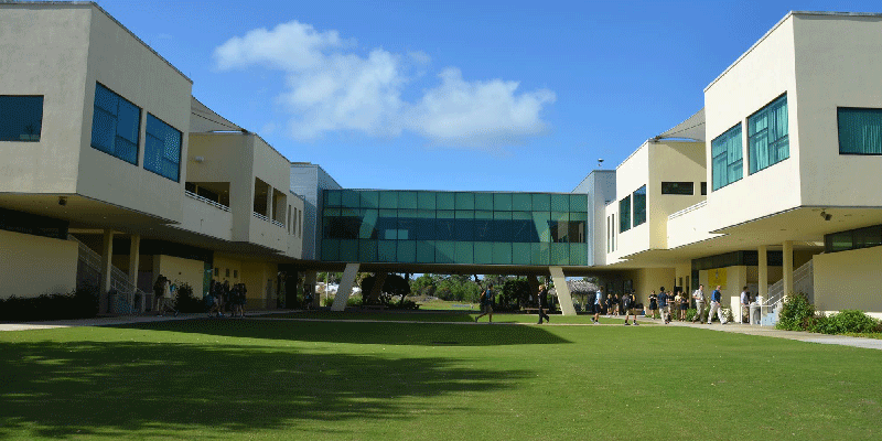 Students walking between two beige buildings