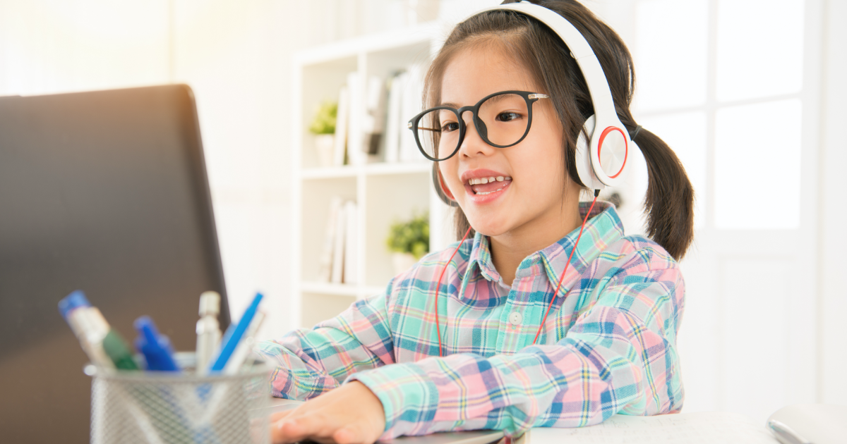 little girl with headphones engaged on laptop