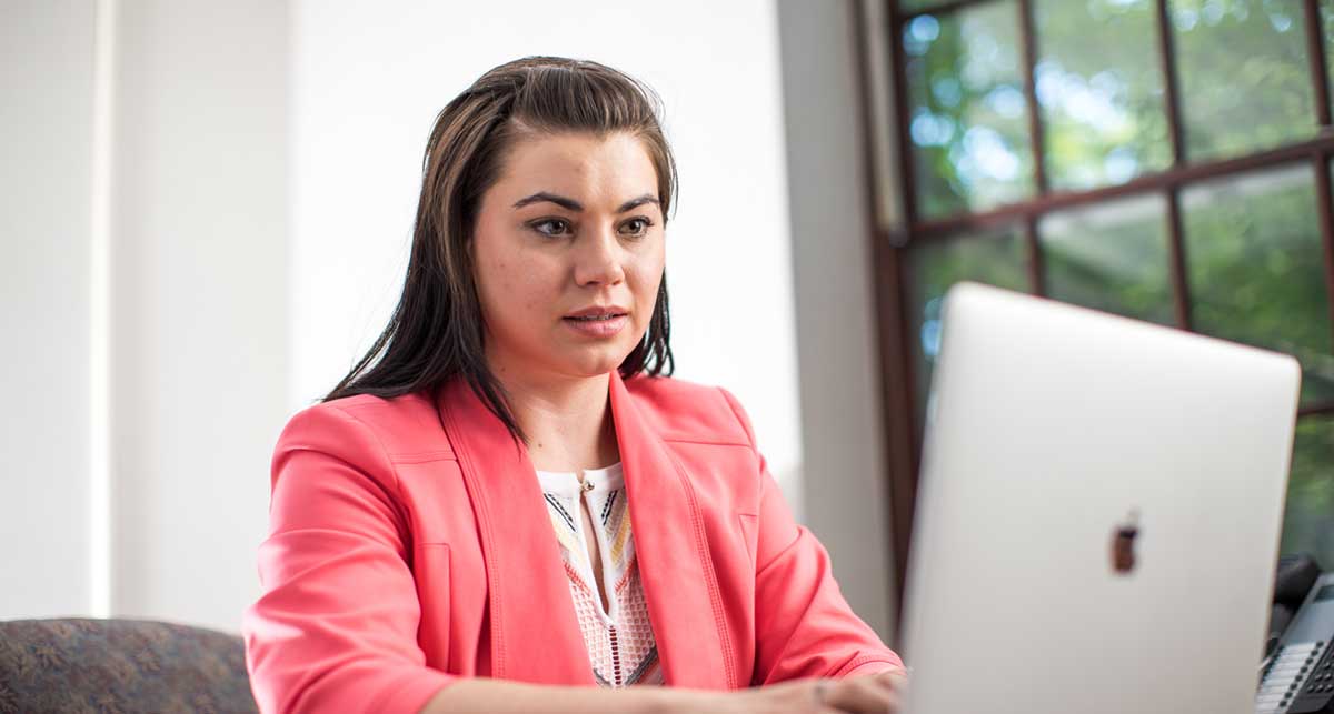 Female teacher in pick blazer on her computer