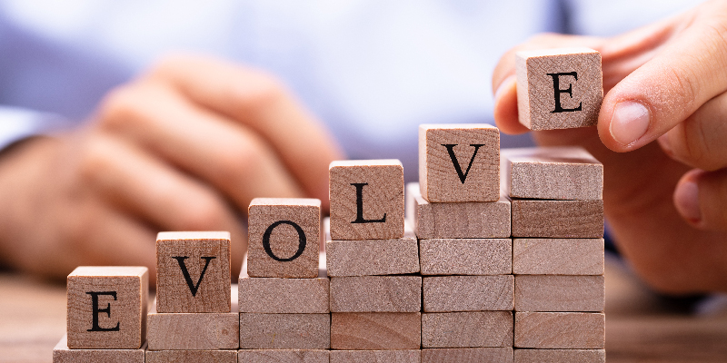 Man building blocks with the word evolve