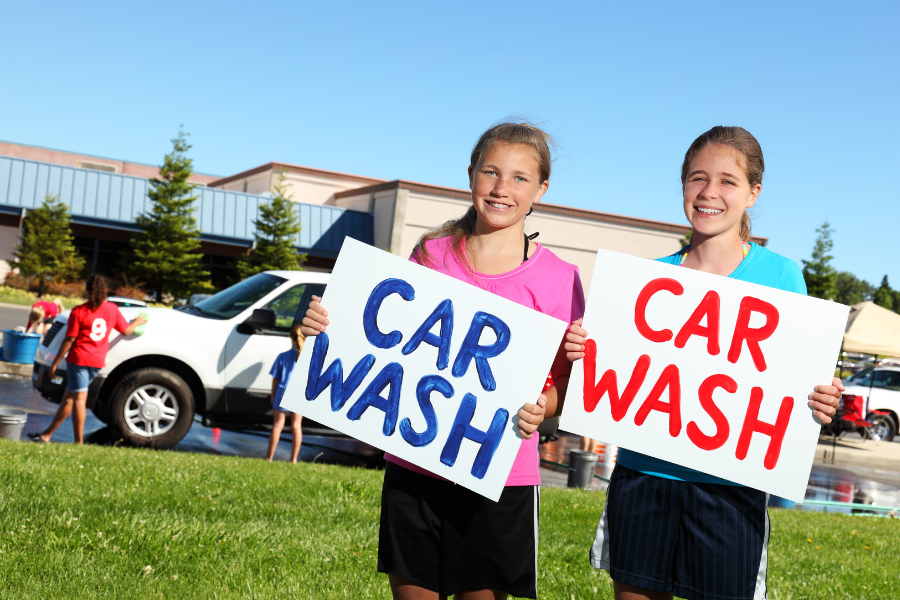 two students holding signs advertising a car wash