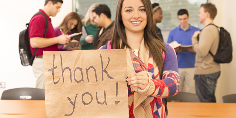 Latin descent college student holds 'Thank you' sign.