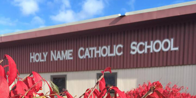 Holy Name Catholic School front of building with beautiful red flowers.