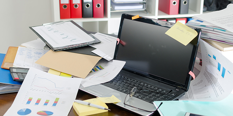 A very messy desk in an office with papers and important information displayed everywhere.