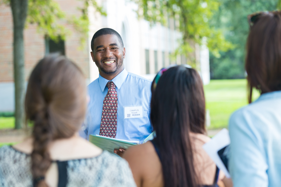 school employee smiling at prospective families during campus tour