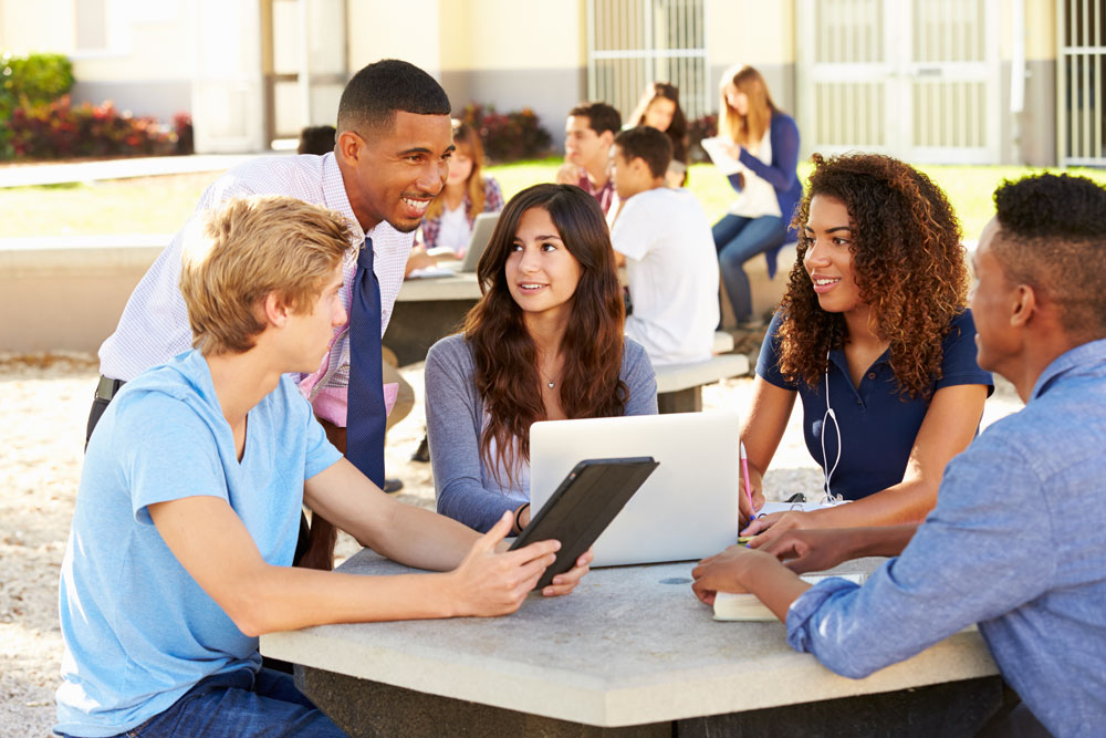 Students at a table with their computer devices