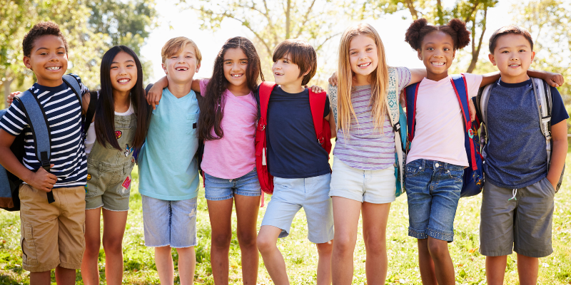 A row of diverse elementary age students smiling
