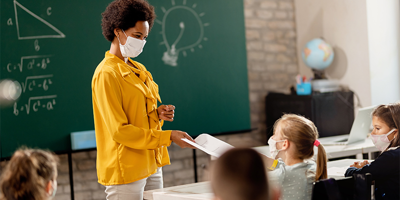 Teacher wearing a mask and teaching her students