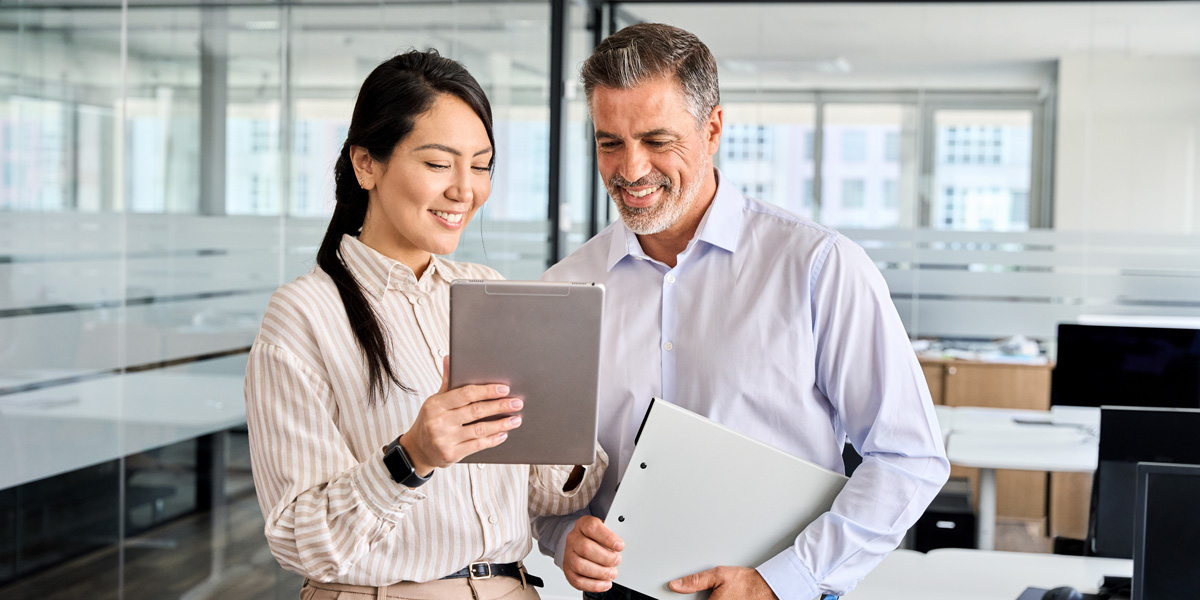 Two smiling coworkers reviewing something on a tablet device